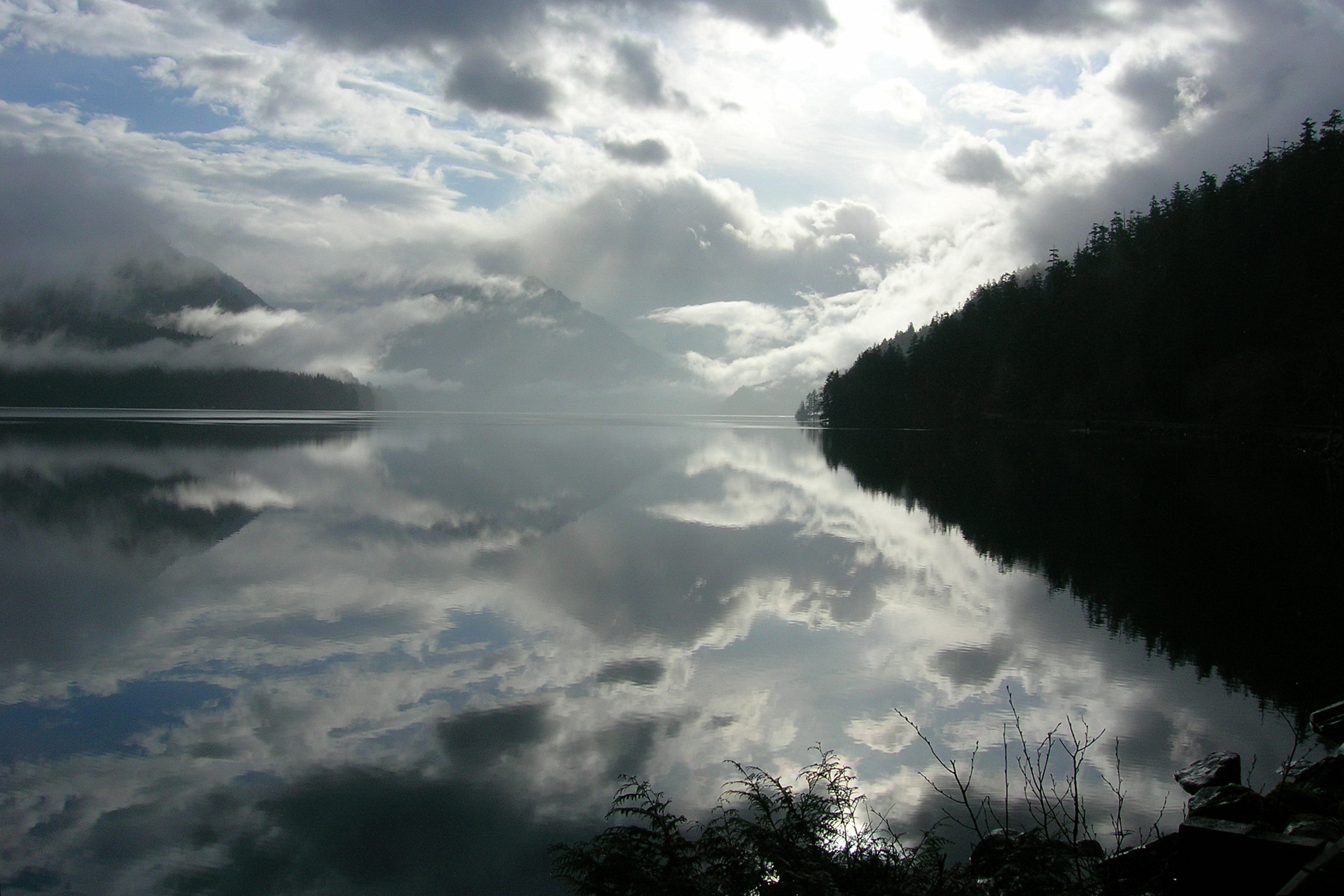 Clouds and forested mountains reflected in the still waters of Lake Crescent, Olympic National Park.